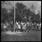 Students Wearing Sashes and Carrying U.S. Flags around a flagpole